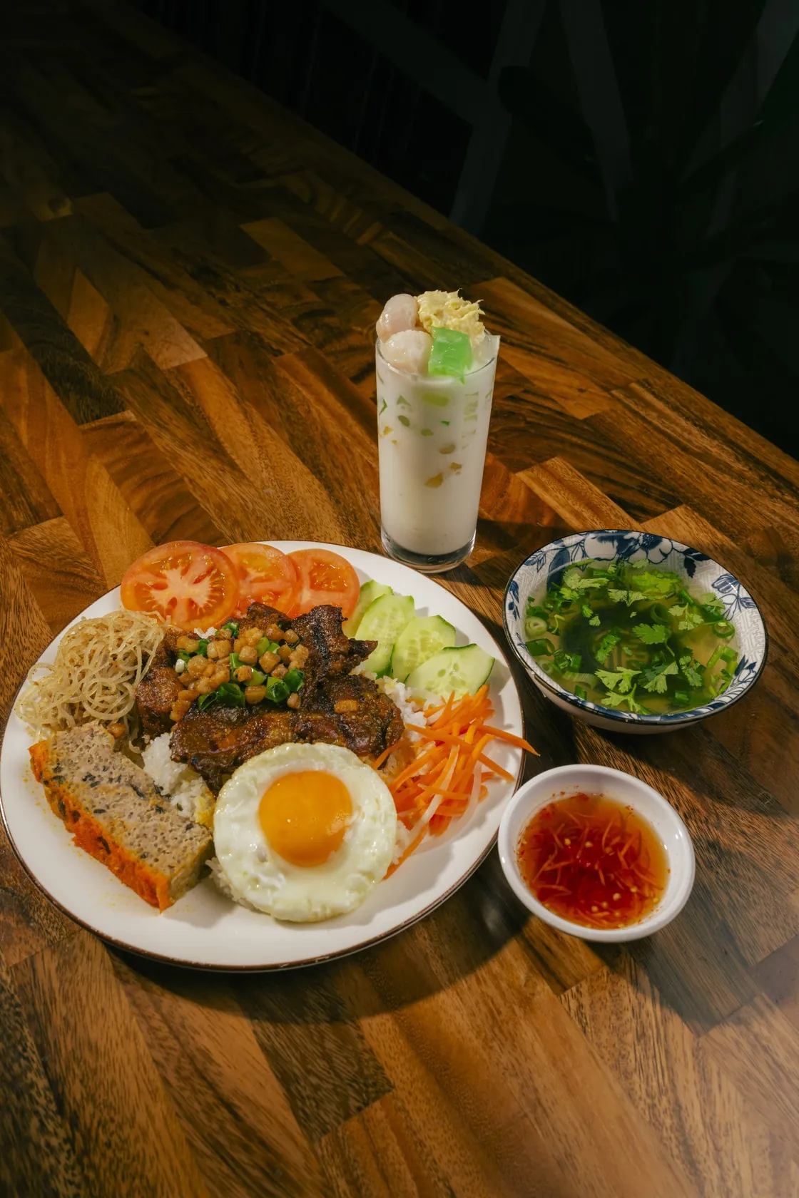 Cơm tấm broken rice with grilled pork, fried egg, chả and bì beside a tall glass of chè thái and clear soup at Bà Năm, Grote Street Adelaide