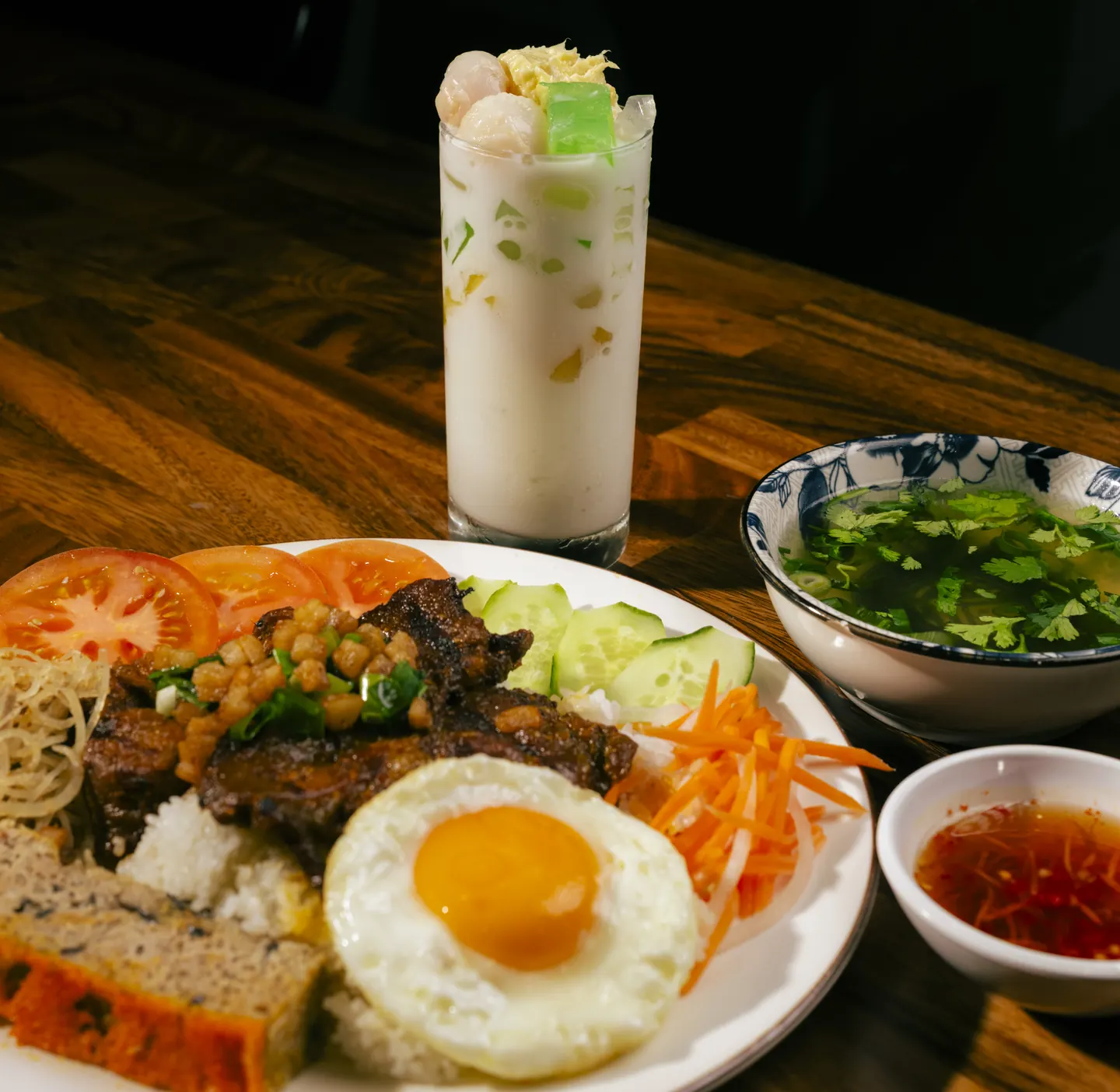Cơm tấm broken rice lunch plate with grilled pork, fried egg, chả, tomato, cucumber and pickled vegetables, served with clear soup, nước chấm and an iced chè dessert drink at Bà Năm, near Adelaide Central Market