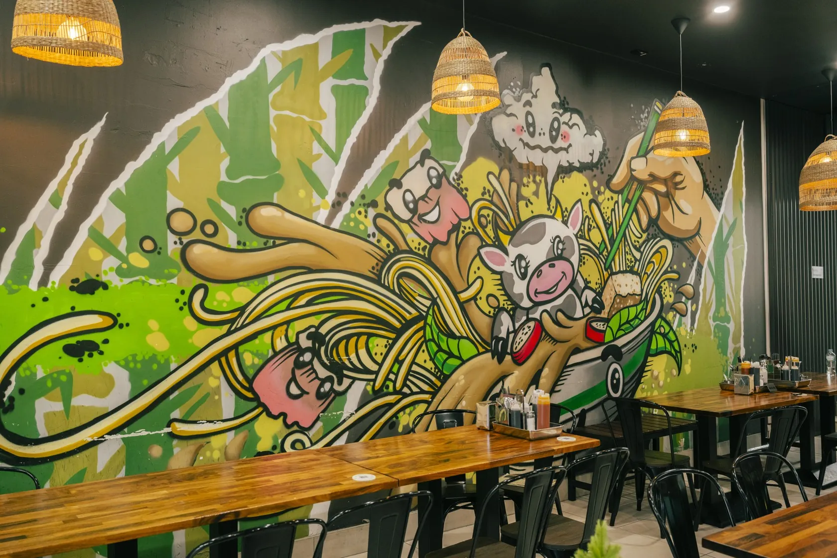 Dining room at Bà Năm Restaurant, Adelaide CBD — warm wooden tables with the restaurant’s cartoon mural wall