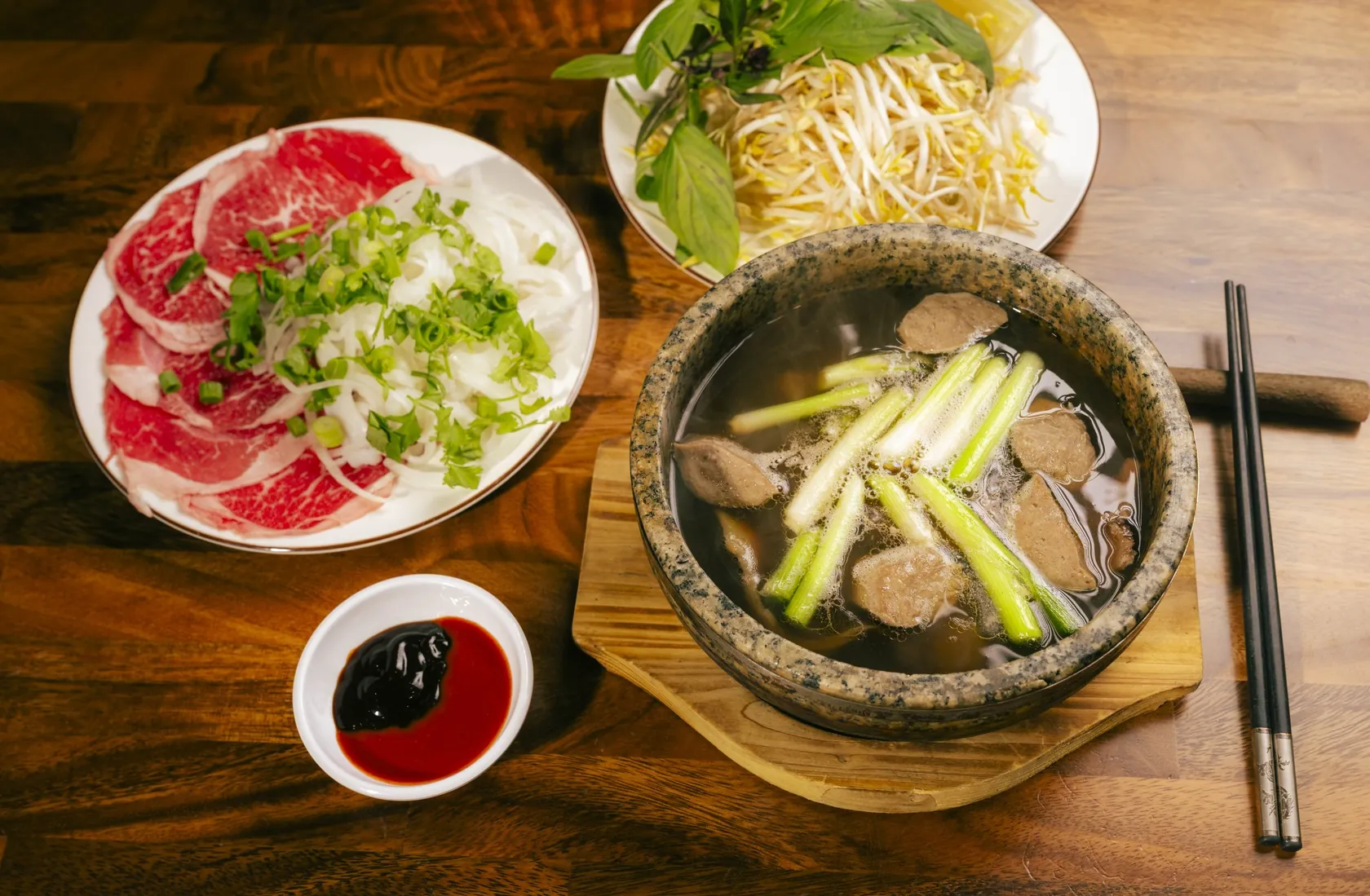 Phở Thố Đá stone-bowl set with beef meatballs and red-coin rare beef plate at Bà Năm — near Pirie Street Adelaide