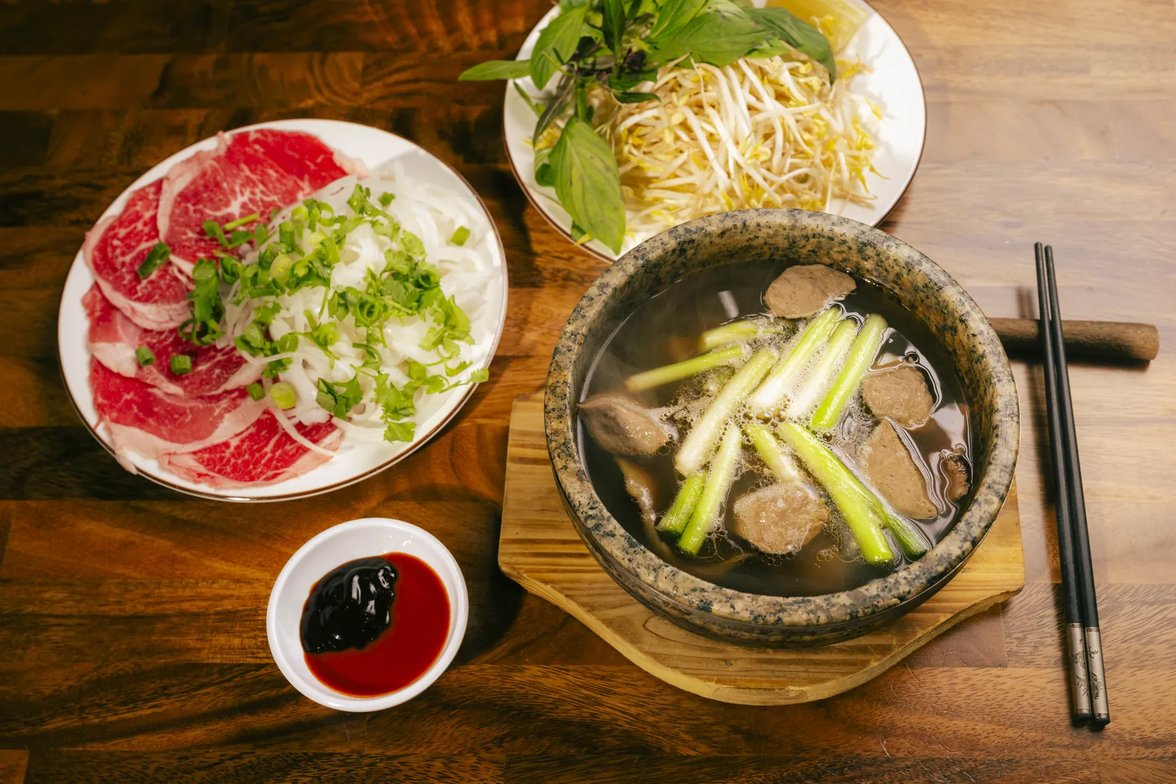 Stone bowl phở with red-coin plate and herbs — trip from Burnside to Bà Năm