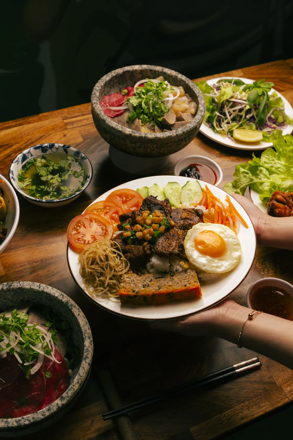 Phở Thố Đá at Bà Năm, 65 Grote Street Adelaide — granite stone bowl of clear beef broth with rare beef, fresh herbs, bean sprouts and lemon, plus a side plate of paper-thin red-coin rare beef with white onion