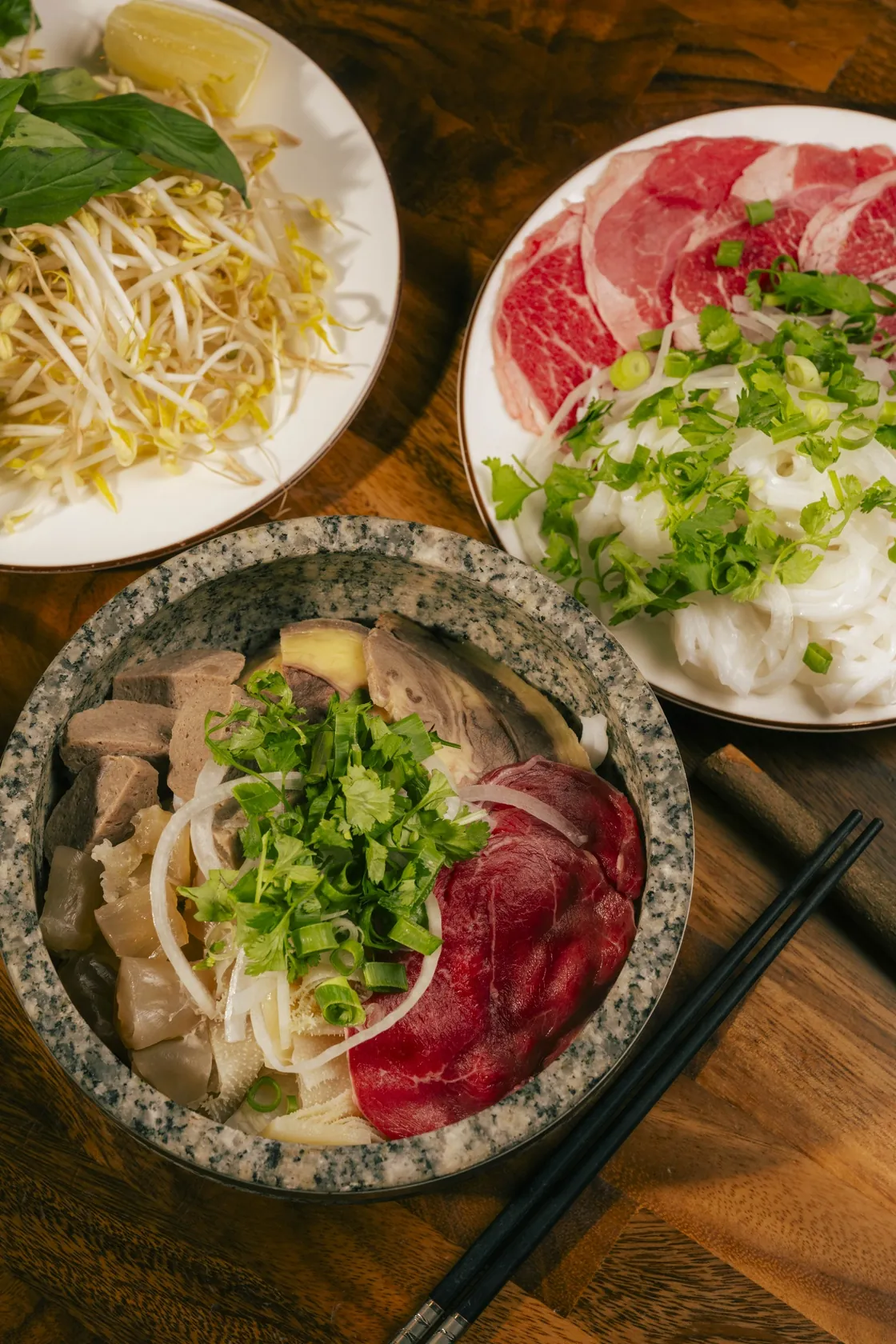 Stone bowl phở with tendon, tripe, rare beef, red-coin plate and herbs — trip from Norwood to Bà Năm