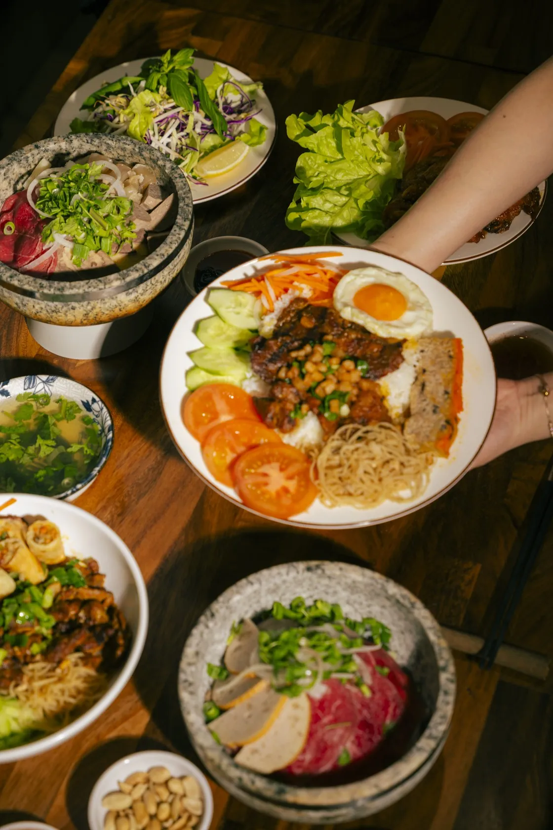 A full winter table at Bà Năm Restaurant, Adelaide — stone-bowl soups, cơm tấm and shared plates being served