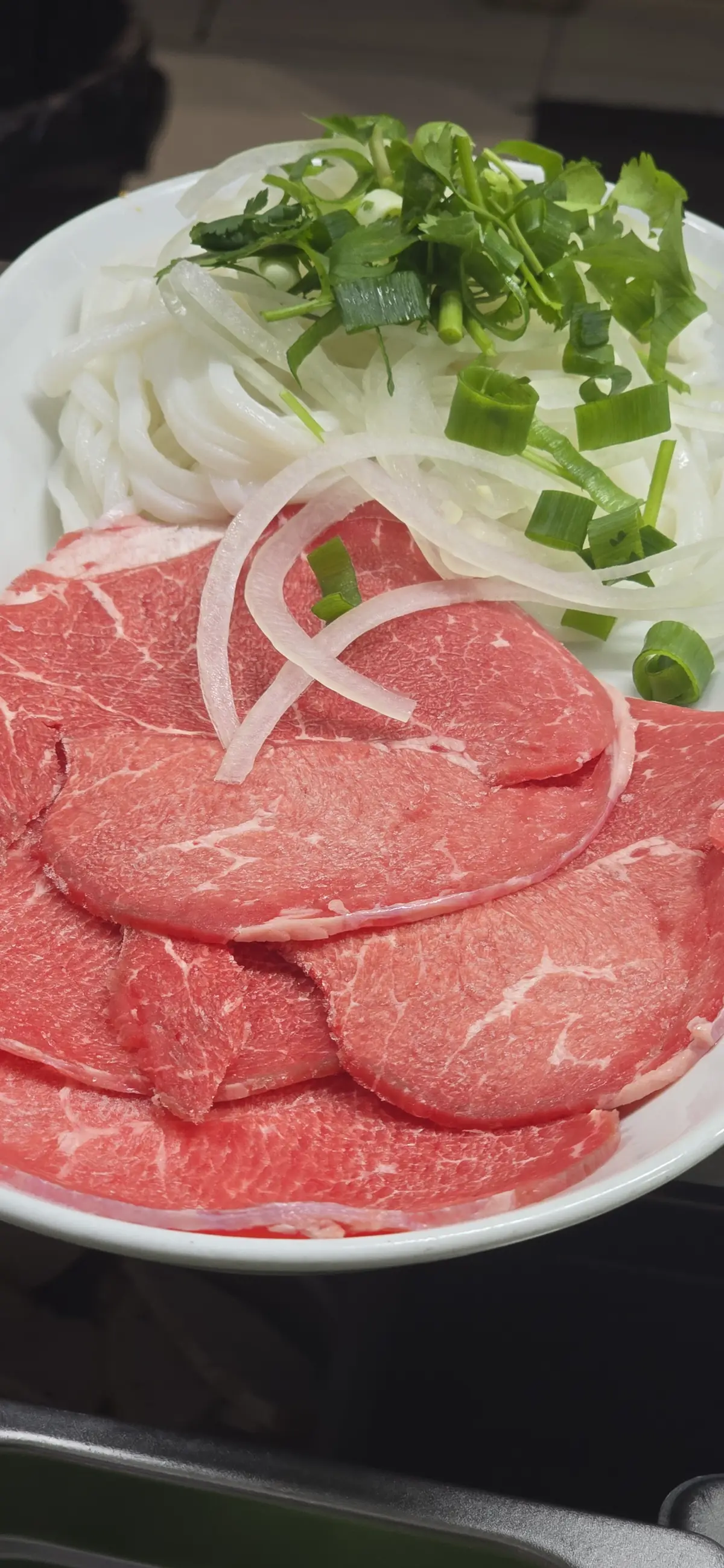 Phở Tái at Bà Năm Adelaide — paper-thin marbled rare beef slices with onion and fresh herbs, ready for the broth pour