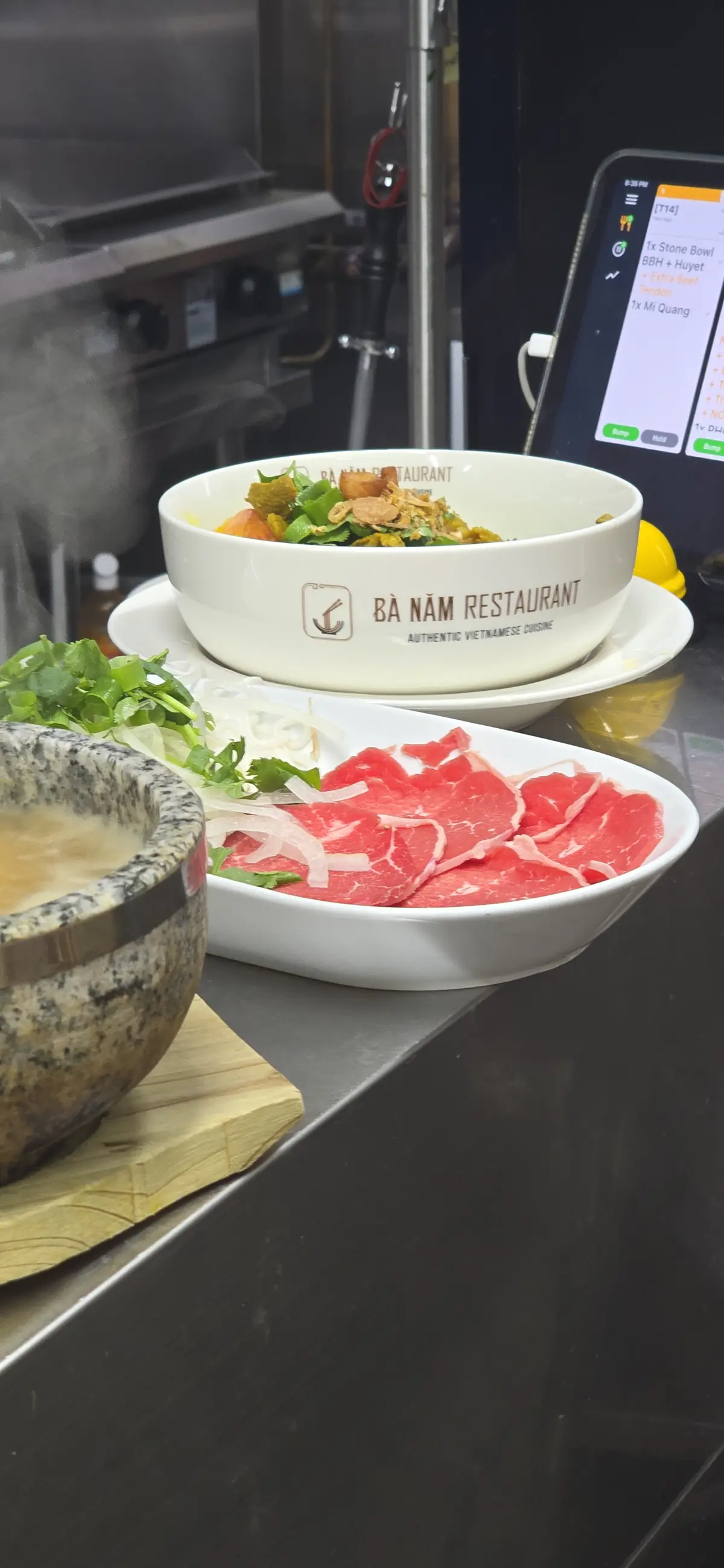 Step two — rare beef platter staged beside a steaming stone bowl, waiting for the broth