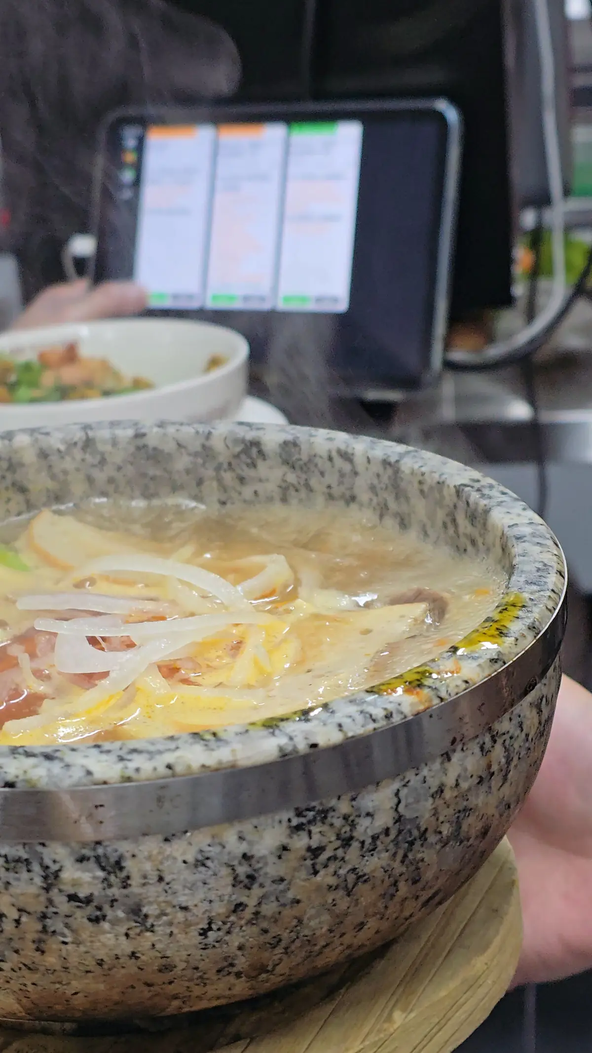 Step three — the stone bowl at the pass, broth still steaming, ready for the table