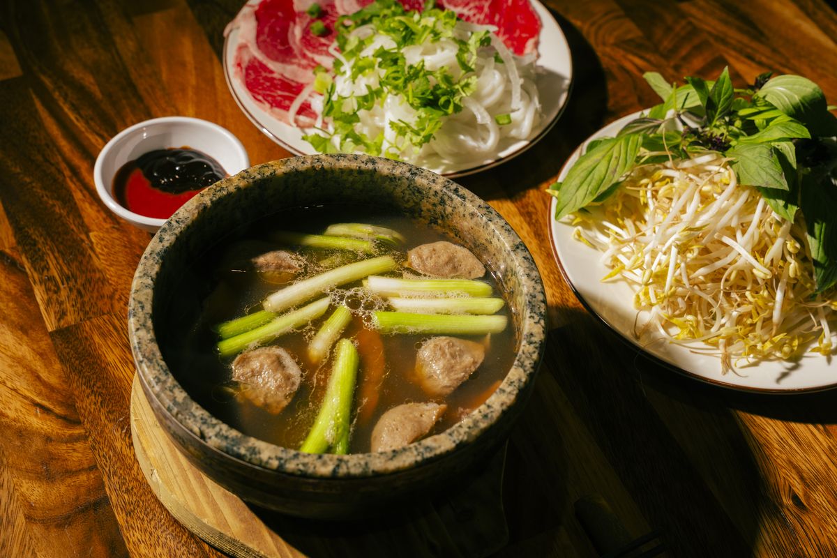 Phở Thố Đá at Bà Năm — signature stone-bowl pho with beef balls and spring onion, still steaming at the table